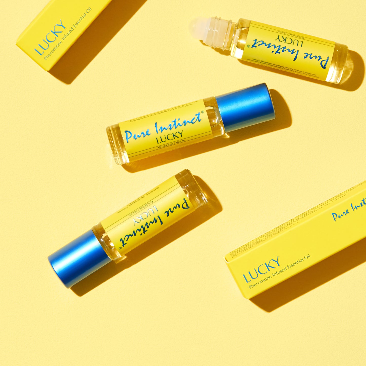 Lucky Roll-On Pheromone Perfume Oil bottles styled on a vibrant yellow background with matching product boxes and caps.