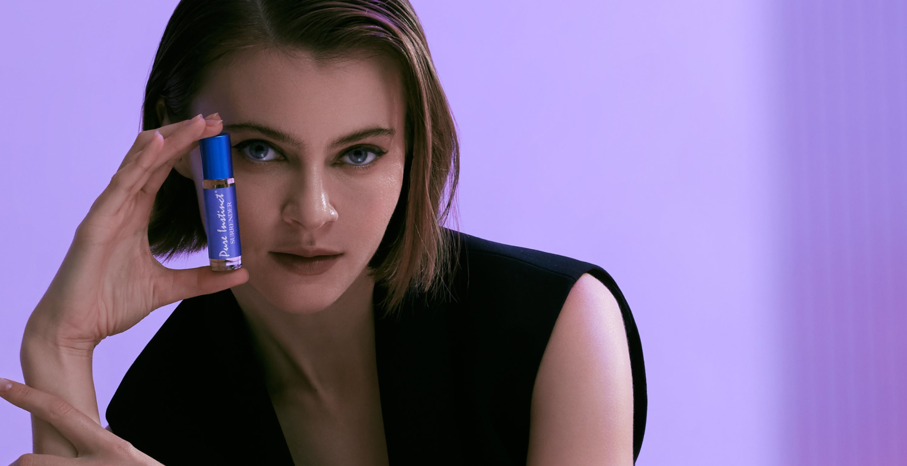 Model holding Pure Instinct Surrender roll-on pheromone perfume near her face.