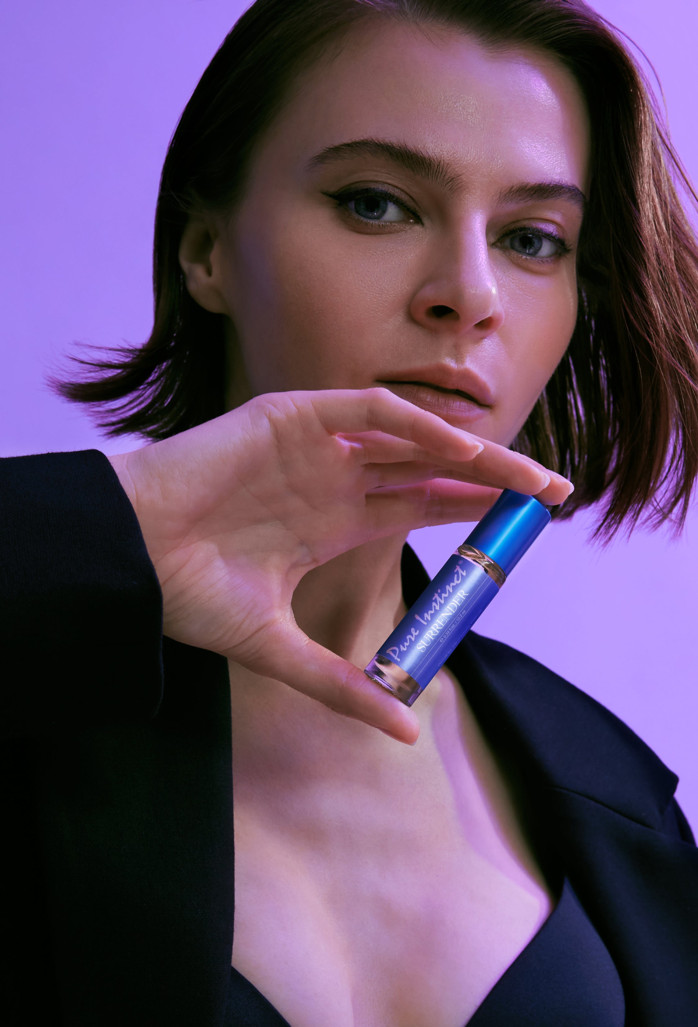 Model holding Pure Instinct Surrender roll-on pheromone perfume near her face.