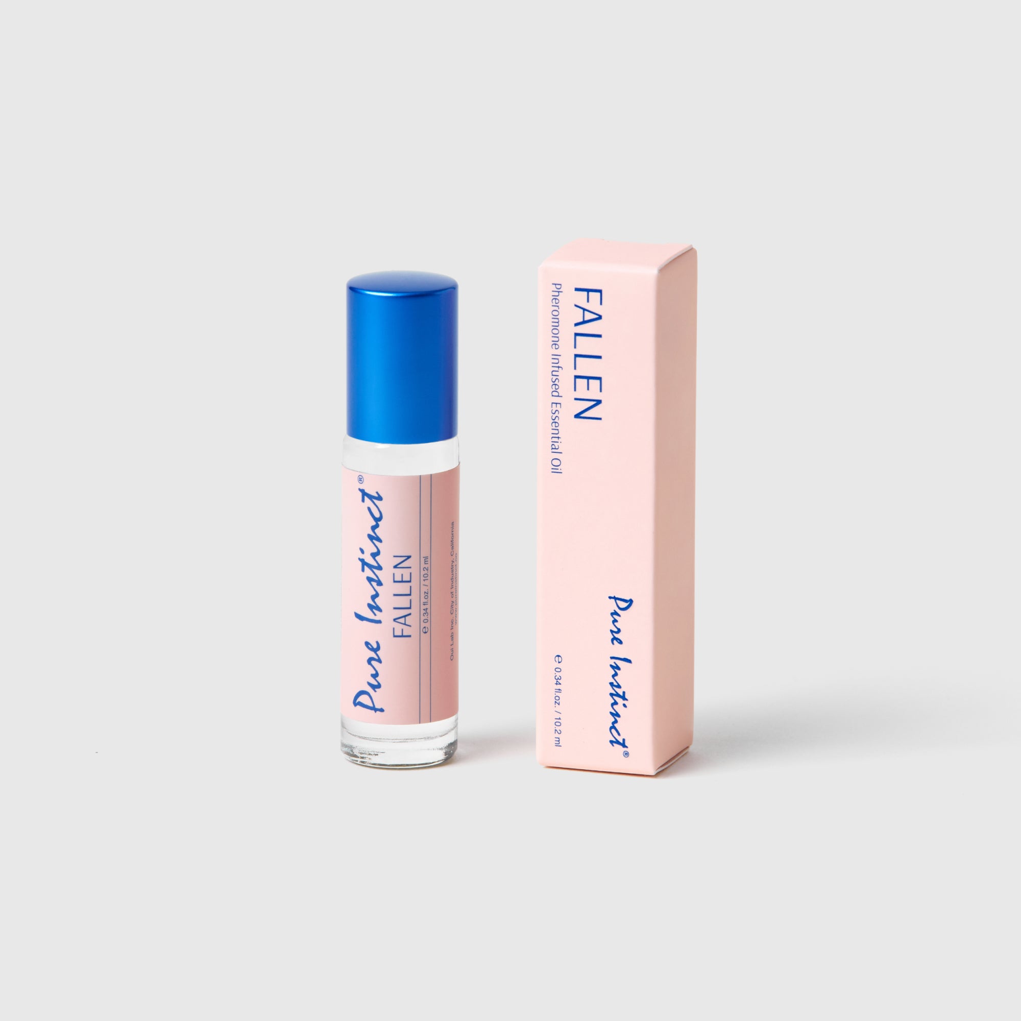 Pure Instinct FALLEN roll-on perfume oil bottles with blue caps arranged on a soft pink background