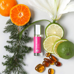 FOR HER Roll-On Pheromone Perfume Oil displayed alongside citrus slices, amber stones, white lily, and cedar leaves — a vibrant visual of its fresh, floral, and sensual scent notes.