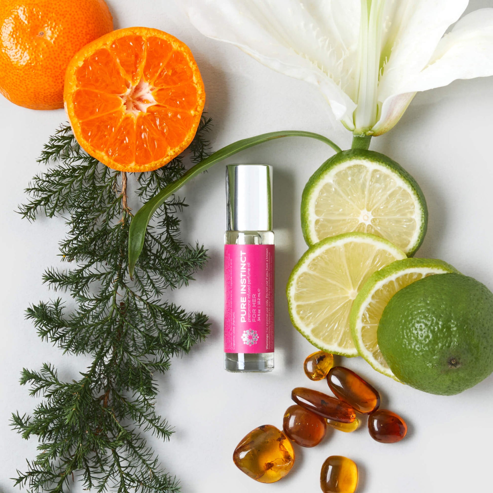 FOR HER Roll-On Pheromone Perfume Oil displayed alongside citrus slices, amber stones, white lily, and cedar leaves — a vibrant visual of its fresh, floral, and sensual scent notes.