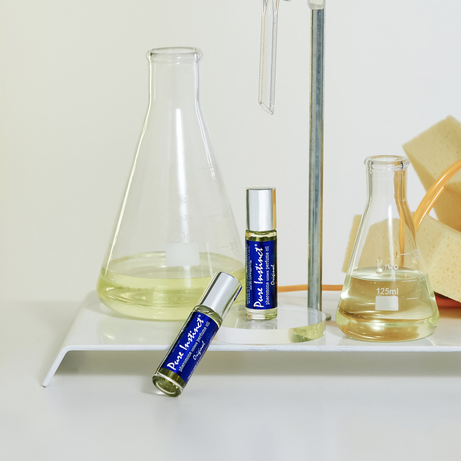 Pure Instinct Original pheromone perfume oil bottles displayed with glass beakers and lab equipment
