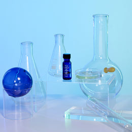Pure Instinct ORIGINAL essential oil bottle placed among laboratory glassware evoking a clean and scientific aesthetic