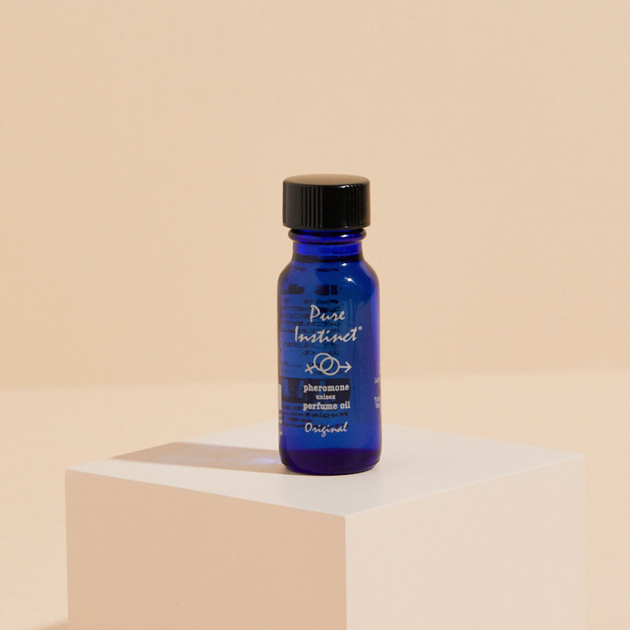 blue glass bottle of Pure Instinct ORIGINAL pheromone infused essential oil displayed on a minimalist pedestal