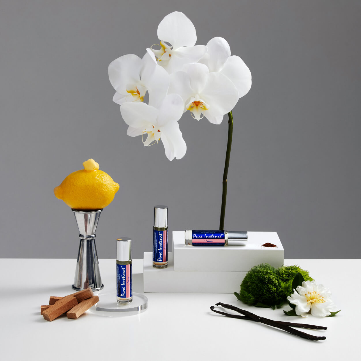 Pure Instinct Crave Roll-On Pheromone Perfume Oil presented among lemon, white orchid, vanilla, and sandalwood elements — a visual expression of the fragrance’s layered and alluring scent profile.